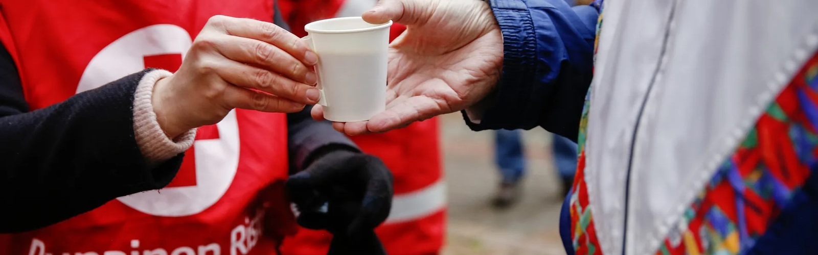 Henkilö ojentaa kuuman kupin toiselle