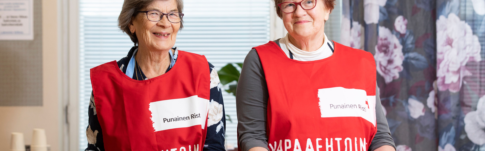 Kaksi vapaaehtoista ruokatarjottiet kädessään.